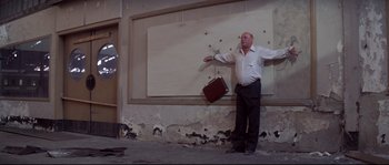 Movie still from “Escape from New York” (1981), directed by John Carpenter – An old man holding a suit case in front of a wall; Wide shot, Low angle