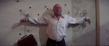 Movie still from “Escape from New York” (1981), directed by John Carpenter – A man standing in front of bullet holes in a wall; Medium shot, Low angle