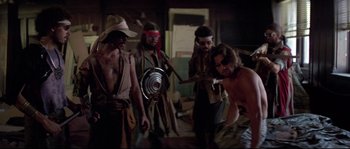 Movie still from “Escape from New York” (1981), directed by John Carpenter – A group of men standing next to each other in a room; Wide shot, Over the shoulder angle