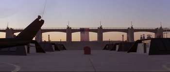 Movie still from “Escape from New York” (1981), directed by John Carpenter – An american flag hanging from a bridge over a river; Extreme Wide shot, High angle