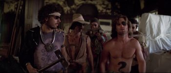 Movie still from “Escape from New York” (1981), directed by John Carpenter – A group of men standing next to each other holding guns; Medium shot, Low angle