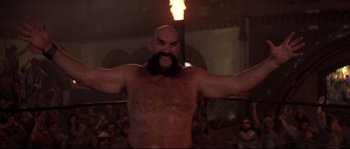 Movie still from “Escape from New York” (1981), directed by John Carpenter – A man with a beard is standing in front of a crowd of people; Medium shot, Low angle
