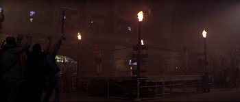 Movie still from “Escape from New York” (1981), directed by John Carpenter – People standing in a boxing ring at night; Extreme Wide shot, Low angle