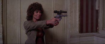 Movie still from “Escape from New York” (1981), directed by John Carpenter – A woman holding a gun in a room; Medium shot, Low angle