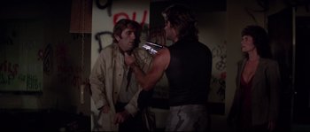 Movie still from “Escape from New York” (1981), directed by John Carpenter – Two men in a room with graffiti on the wall; Medium shot, Over the shoulder angle