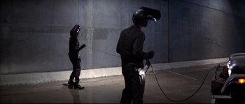 Movie still from “Escape from New York” (1981), directed by John Carpenter – Two men in black suits and helmets are welding together; Wide shot, High angle