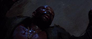 Movie still from “Escape from New York” (1981), directed by John Carpenter – A man with a chain around his neck and chest; Close Up shot, Overhead angle
