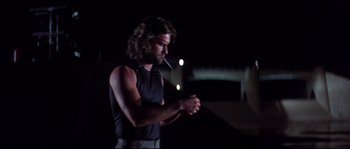 Movie still from “Escape from New York” (1981), directed by John Carpenter – A man smoking a cigarette while standing in the dark at night; Medium shot, Low angle