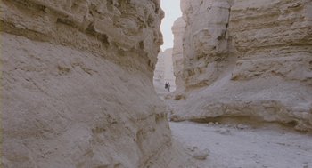 Movie still from “Essential Killing” (2010), directed by Jerzy Skolimowski – A person is walking through a canyon in the desert; Extreme Wide shot, Low angle
