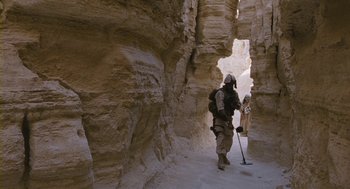 Movie still from “Essential Killing” (2010), directed by Jerzy Skolimowski – A man with a backpack walking through a cave; Wide shot, High angle