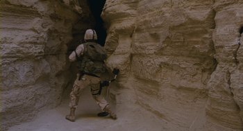 Movie still from “Essential Killing” (2010), directed by Jerzy Skolimowski – A man in a desert area with a rifle; Wide shot, High angle
