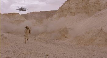 Movie still from “Essential Killing” (2010), directed by Jerzy Skolimowski – A man in a white suit walking in the dirt; Extreme Wide shot, Low angle