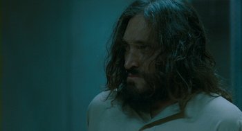 Movie still from “Essential Killing” (2010), directed by Jerzy Skolimowski – A person with long hair and a beard; Close Up shot, Over the shoulder angle