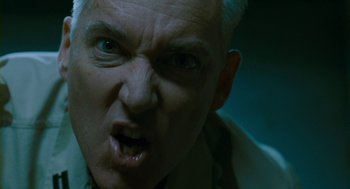 Movie still from “Essential Killing” (2010), directed by Jerzy Skolimowski – An older man with a white hair and a blue jacket; Close Up shot, Low angle
