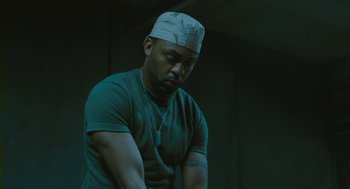 Movie still from “Essential Killing” (2010), directed by Jerzy Skolimowski – A man with a white hat is looking down; Medium shot, Low angle