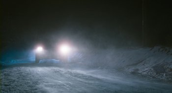 Movie still from “Essential Killing” (2010), directed by Jerzy Skolimowski – A car driving on a snowy road at night; Extreme Wide shot, High angle
