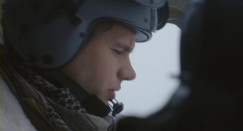 Movie still from “Essential Killing” (2010), directed by Jerzy Skolimowski – A young man wearing a helmet while sitting in an airplane; Close Up shot, Over the shoulder angle