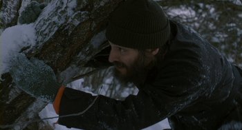 Movie still from “Essential Killing” (2010), directed by Jerzy Skolimowski – A man with a beard is leaning against a tree; Medium shot, Low angle