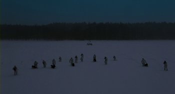 Movie still from “Essential Killing” (2010), directed by Jerzy Skolimowski – A group of people standing on top of a snow covered field; Extreme Wide shot, High angle