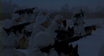 Movie still from “Essential Killing” (2010), directed by Jerzy Skolimowski – A group of men in winter clothing with guns and a dog; Wide shot, High angle