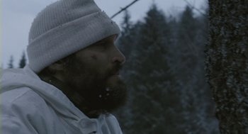 Movie still from “Essential Killing” (2010), directed by Jerzy Skolimowski – A man with a beard wearing a white hat; Close Up shot, Low angle