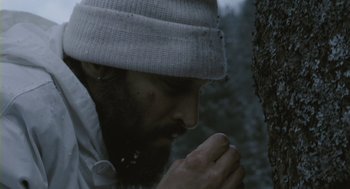 Movie still from “Essential Killing” (2010), directed by Jerzy Skolimowski – A man with a beard wearing a hat and praying; Close Up shot, Low angle