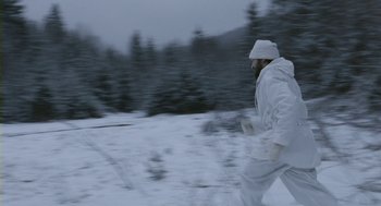 Movie still from “Essential Killing” (2010), directed by Jerzy Skolimowski – A man in a white suit running in the snow; Wide shot, High angle
