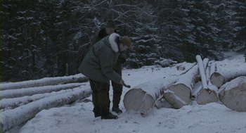 Movie still from “Essential Killing” (2010), directed by Jerzy Skolimowski – A man and a woman in the snow near a pile of logs; Wide shot, Over the shoulder angle