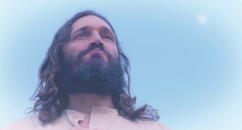 Movie still from “Essential Killing” (2010), directed by Jerzy Skolimowski – A man with long hair and a long beard looking upward; Close Up shot, Low angle