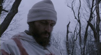 Movie still from “Essential Killing” (2010), directed by Jerzy Skolimowski – A man with a beard wearing a white hat; Close Up shot, Low angle