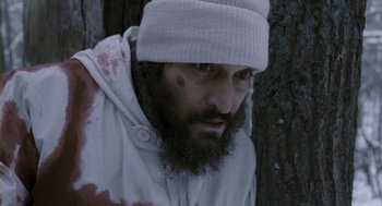 Movie still from “Essential Killing” (2010), directed by Jerzy Skolimowski – A man with a beard wearing a white hat; Close Up shot, High angle