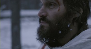 Movie still from “Essential Killing” (2010), directed by Jerzy Skolimowski – A man with a long beard and a cross on his forehead; Close Up shot, Low angle