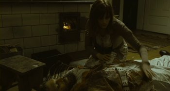 Movie still from “Essential Killing” (2010), directed by Jerzy Skolimowski – A woman kneeling down next to a dead body; Medium shot, High angle
