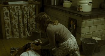 Movie still from “Essential Killing” (2010), directed by Jerzy Skolimowski – A woman kneeling on the ground in a kitchen; Medium shot, High angle