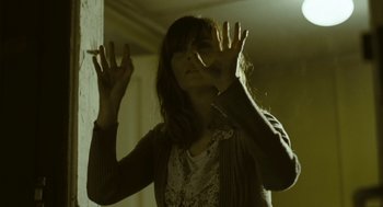 Movie still from “Essential Killing” (2010), directed by Jerzy Skolimowski – A woman is holding a cigarette in her hands; Medium shot, Low angle