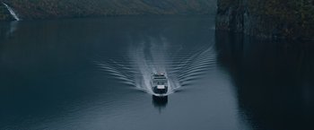 Movie still from “The Quake” (2018), directed by John Andreas Andersen – A boat traveling across a body of water near mountains; Extreme Wide shot, High angle