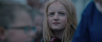 Movie still from “The Quake” (2018), directed by John Andreas Andersen – A young girl with long blonde hair wearing headphones; Close Up shot, Low angle