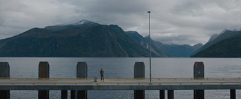Movie still from “The Quake” (2018), directed by John Andreas Andersen – A person standing on a pier near a body of water; Extreme Wide shot, Low angle
