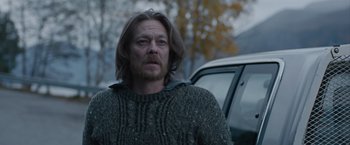 Movie still from “The Quake” (2018), directed by John Andreas Andersen – A man with long hair standing in front of a car; Medium shot, Over the shoulder angle