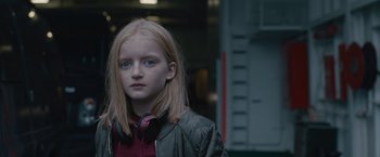 Movie still from “The Quake” (2018), directed by John Andreas Andersen – A young girl wearing headphones and a jacket; Close Up shot, Over the shoulder angle