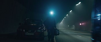 Movie still from “The Quake” (2018), directed by John Andreas Andersen – A man walking down a street with a car in front of him; Wide shot, Low angle