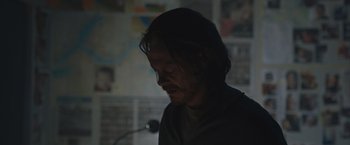Movie still from “The Quake” (2018), directed by John Andreas Andersen – A man with long dark hair standing in a dark room; Close Up shot, Over the shoulder angle