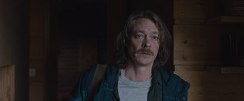 Movie still from “The Quake” (2018), directed by John Andreas Andersen – A man with long brown hair and a mustache; Close Up shot, Over the shoulder angle