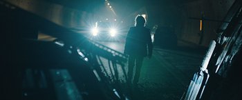 Movie still from “The Quake” (2018), directed by John Andreas Andersen – A person walking on a street at night with cars behind them; Wide shot, Low angle