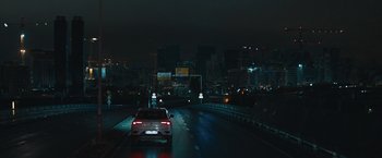 Movie still from “The Quake” (2018), directed by John Andreas Andersen – A car driving down a street at night; Extreme Wide shot, High angle