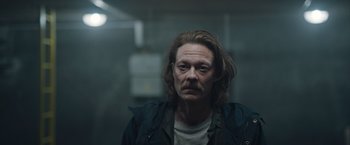 Movie still from “The Quake” (2018), directed by John Andreas Andersen – A man with long brown hair and a beard; Close Up shot, Low angle