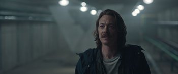 Movie still from “The Quake” (2018), directed by John Andreas Andersen – A man with long brown hair and a mustache; Close Up shot, Over the shoulder angle