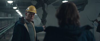 Movie still from “The Quake” (2018), directed by John Andreas Andersen – A man in a hard hat pointing at something; Medium shot, Over the shoulder angle