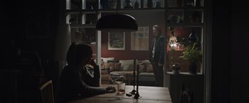 Movie still from “The Quake” (2018), directed by John Andreas Andersen – A man standing in a living room next to a table; Wide shot, Low angle
