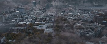 Movie still from “The Quake” (2018), directed by John Andreas Andersen – An aerial view of a city with smoke coming out of it; Extreme Wide shot, High angle